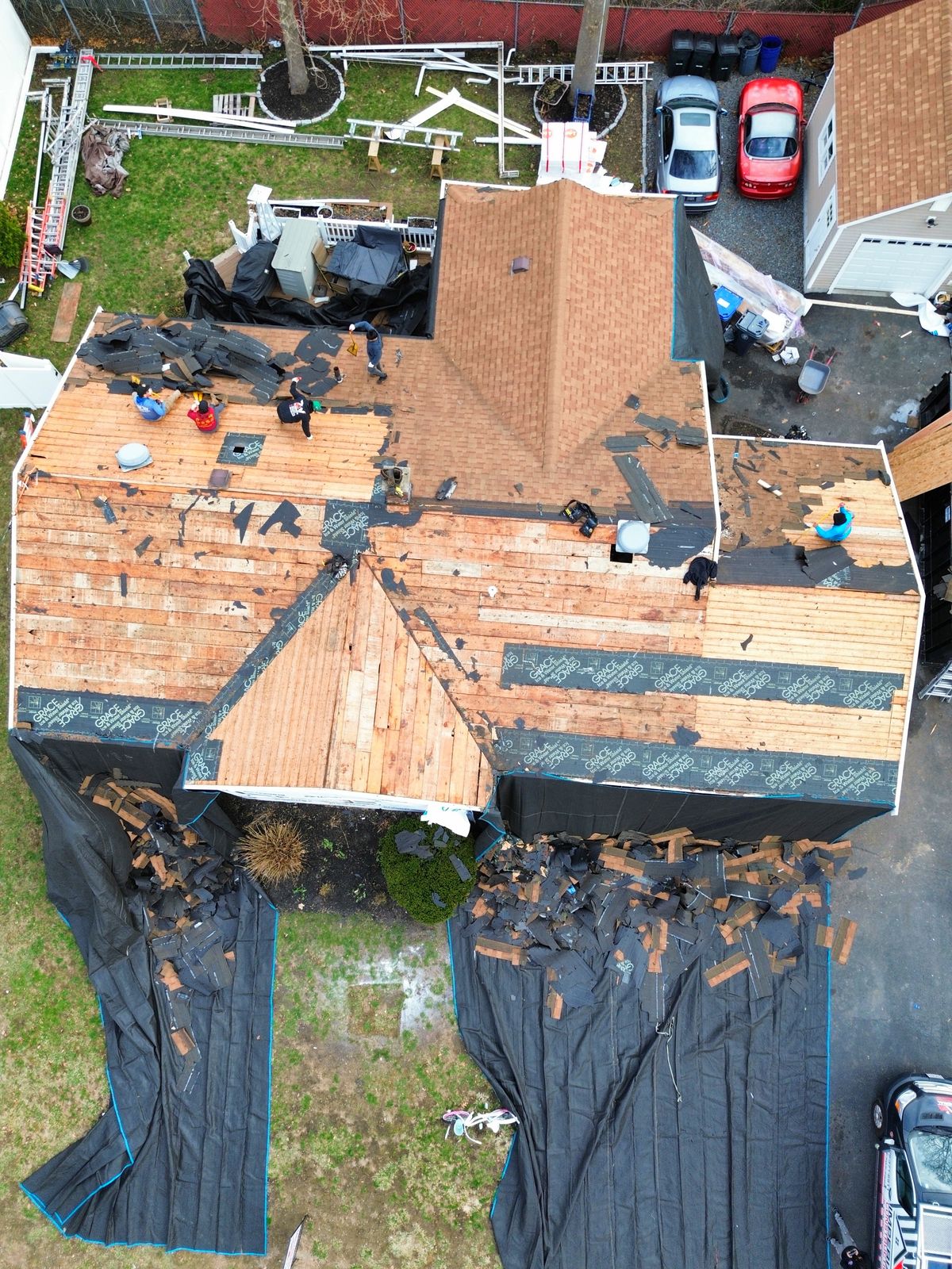 Tear-off in progress with property fully protected by tarps